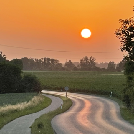 Kurvige Landstraße bei Sonnenuntergang in ländlicher Landschaft